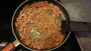 A frying pan with browned minced meat.