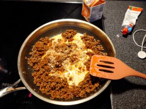 A skillet with the fried minced meat, some dashes tomato puree, and a couple splashes of heavy cream.