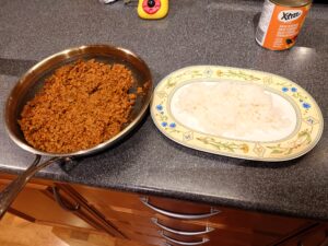 A skillet with a minced meat mixture and a serving plate with rice.