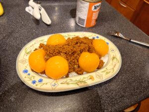Sliced canned peaches on top of the minced meat mix on the serving plate.