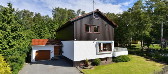 Et hvitt og mørkebrunt hus med garasje. gårdsplass, og grønn plen.