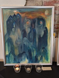 Bildet viser et maleri med blå hus som også skjuler et hestefjes, øyne, og fugler. Rundt husene er det gult og rødt som i en solnedgang. 